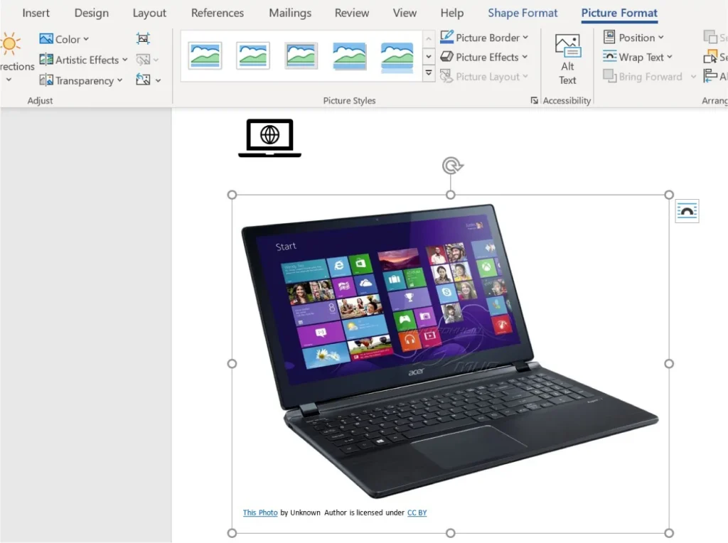 Screenshot of a Microsoft Word document with an image of an Acer laptop displaying the Windows 8 Start screen. The 'Picture Format' tab is selected, showing options for picture styles, borders, effects, and layout. A caption below the image reads, 'This Photo by Unknown Author is licensed under CC BY.