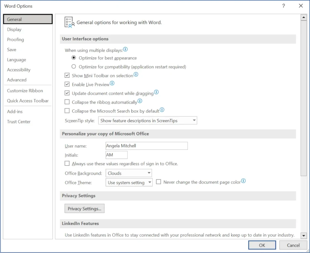 A screenshot of the Word Options dialog box in Microsoft Word with the General tab selected. It displays settings under "General options for working with Word," including user interface options like optimizing for best appearance, showing the Mini Toolbar, enabling Live Preview, and collapsing the ribbon. The personalization section shows the user name as Angela Mitchell with initials AM, Office Background set to Clouds, and Office Theme set to Use system setting. Additional sections include Privacy Settings and LinkedIn Features, with OK and Cancel buttons at the bottom.
