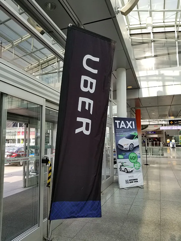 Outside at an airport pickup showing an Uber banner and down aways a taxi banner