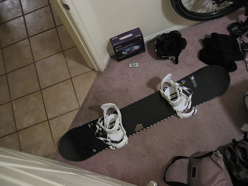 Overhead shot of a person's snowboard and boots in the entryway of their home.