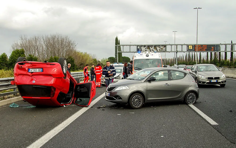 A photo shows a car accident on a highway with one car flipped over on its roof.