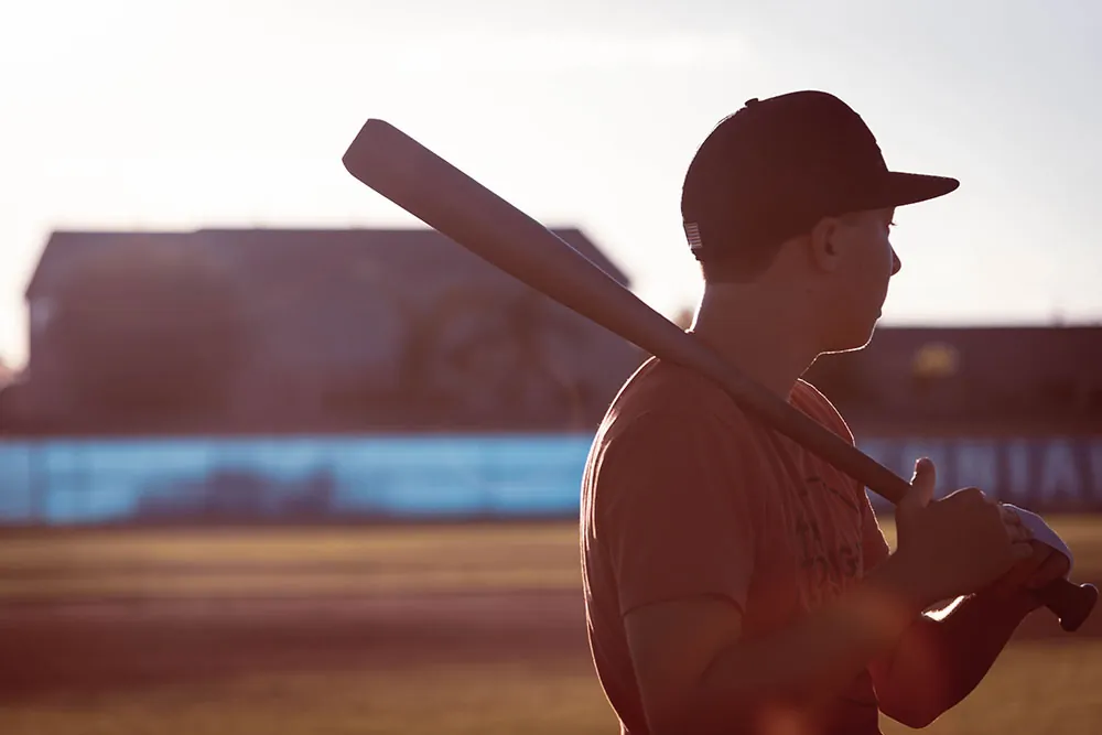 A young man on a baseball field holds a bat.
