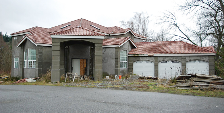Photo of an unfinished house with construction materials scattered.
