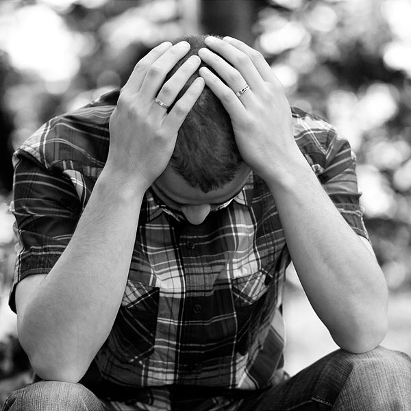 Photo of a person sitting, leaning forward with head in hands