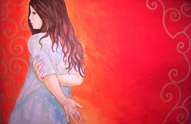 "A painting of a person with long, wavy brown hair wearing a light blue dress with white star patterns. The person is embracing themselves, arms crossed over their chest and hands gripping their upper arms. The background features a warm gradient from orange to red with decorative swirls in the corners."