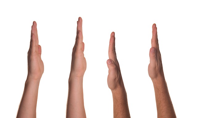 "Four hands are shown vertically with palms facing each other in a 'high five' gesture. The hands are aligned side by side against a white background, each with a different skin tone to represent diversity."