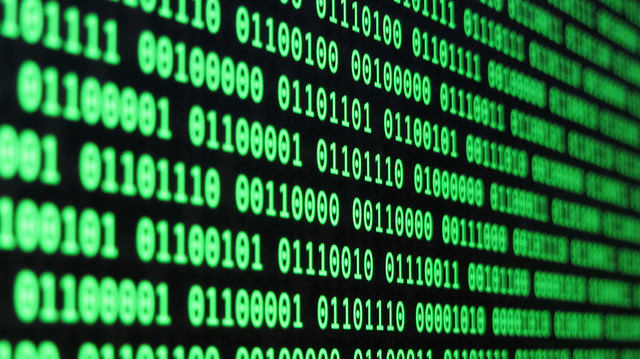 "Close-up of a computer screen displaying rows of binary code made up of 0s and 1s. The text appears in bright green on a black background, evoking a classic 'hacker' aesthetic."