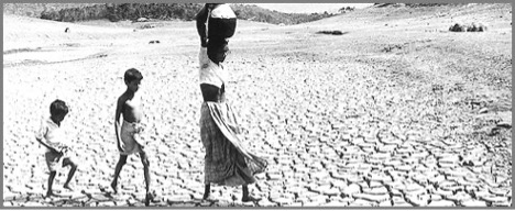 Women and two young children (boys) walking through what appears to be a dried body of water