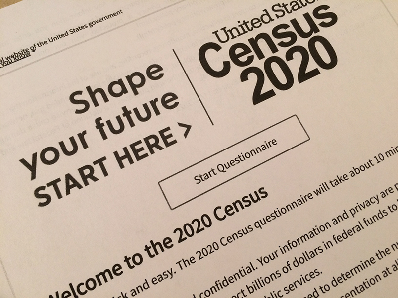A close-up of a printed document from the United States Census 2020. The document features bold text that reads 'Shape your future START HERE >' alongside the 'United States Census 2020' title. Below this, there is a button labeled 'Start Questionnaire.' The text on the document provides information about the 2020 Census, encouraging participation and explaining its importance. The document is printed on standard white paper with black text.