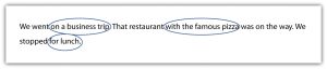 "The image shows a sentence with two phrases circled. The sentence reads: 'We went on a business trip. That restaurant with the famous pizza was on the way. We stopped for lunch.' The phrases 'a business trip' and 'for lunch' are circled in blue ink."