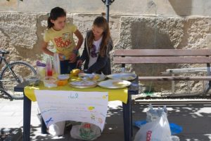 Two young girls setting up a lemonade stand.