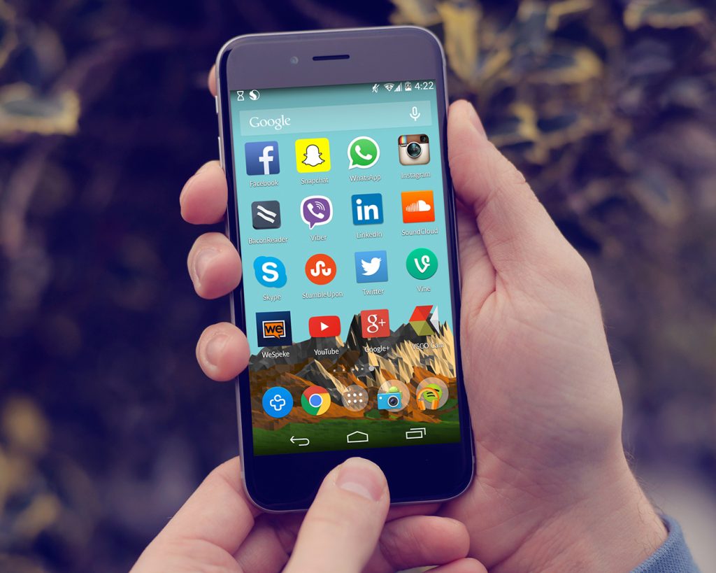 Photo of a close up of a person holding a smartphone. A variety of apps are displayed.