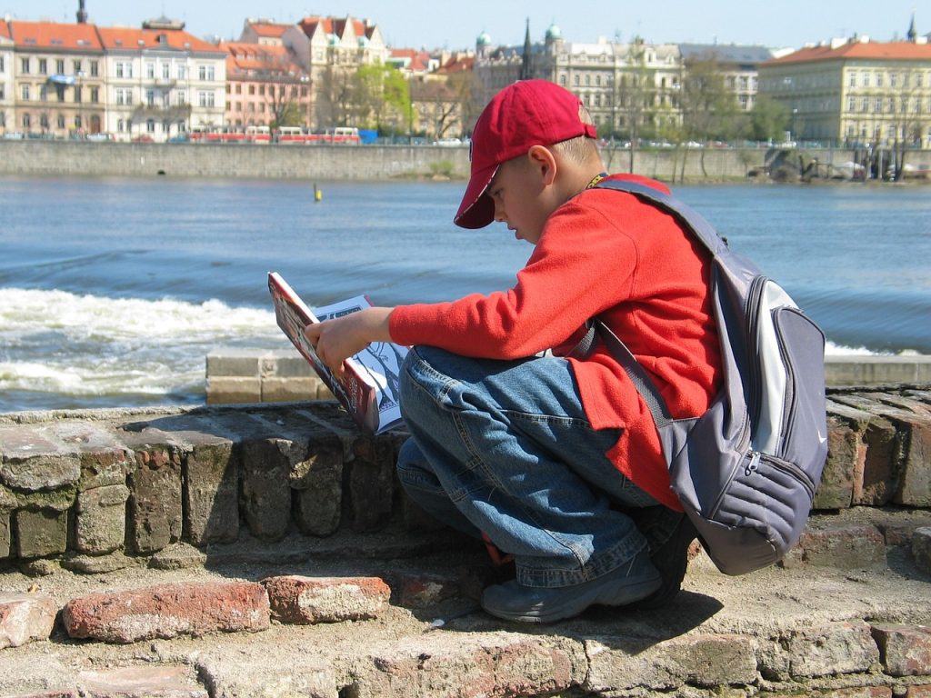 Photo of person kneeling down next to water examining a book. 
