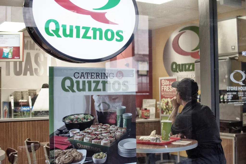 Photo of a customer sitting inside a Quiznos store. 