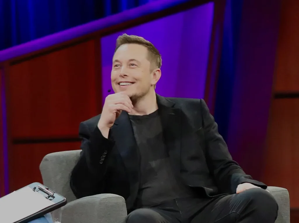Photo of Elon Musk sitting in a chair.