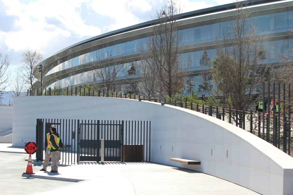 View of a building with two people standing outside next to a gate talking.