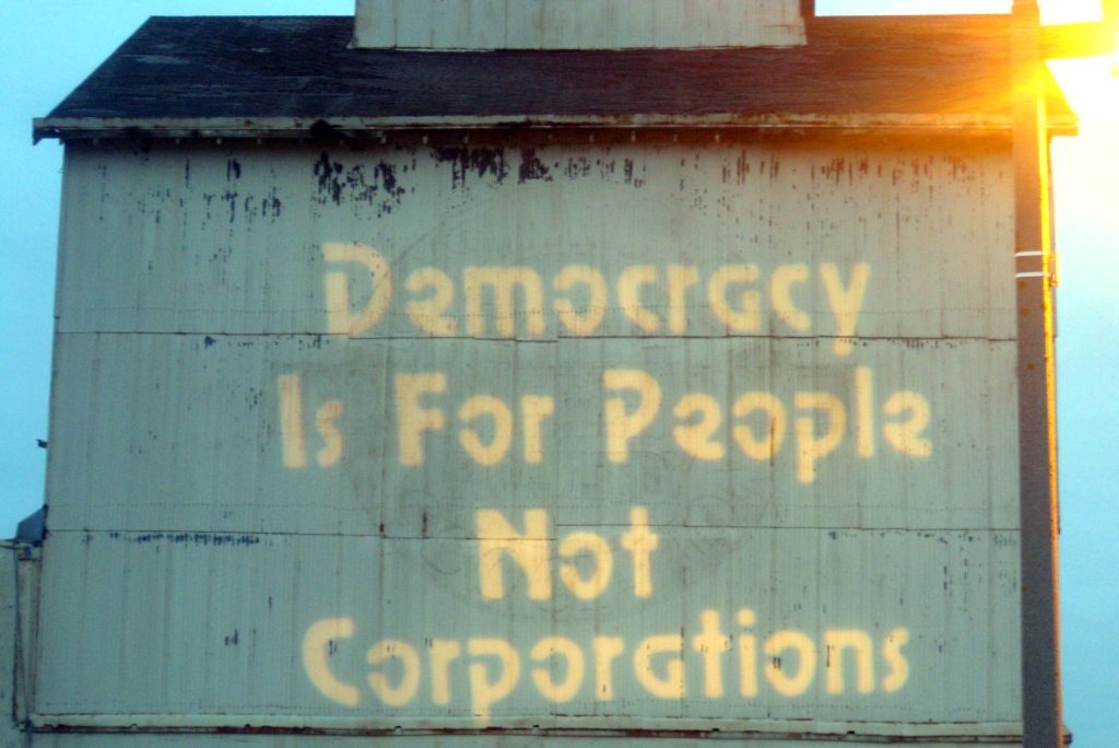 Projected on a sign it says 'Democracy is for People Not Corporations'